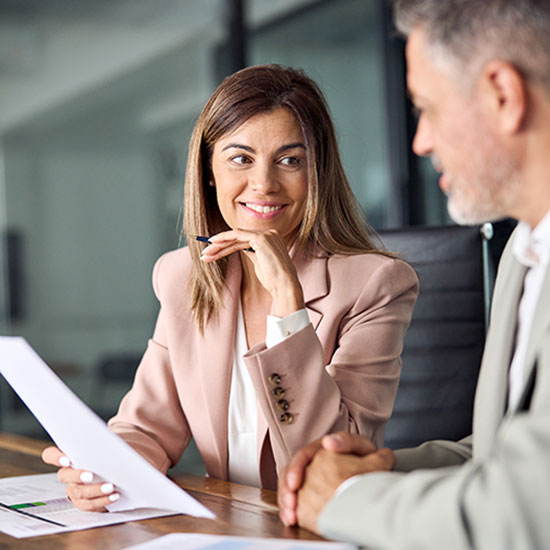 Woman in office holding paperwork while talking to man